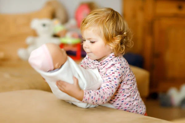 Entzückende süße kleine Mädchen, die mit Puppe spielen. Glückliches gesundes Baby, das Spaß am Rollenspiel hat, die Mutter zu Hause oder im Kinderzimmer spielt. Aktive Tochter mit Spielzeug. — Stockfoto