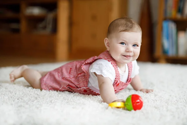 Niedliches Baby, das mit buntem Rasselspielzeug spielt. Kleines Mädchen blickt in die Kamera und krabbelt — Stockfoto