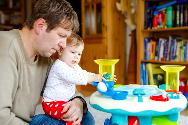 Gelukkig trotse jonge vader plezier met baby dochter, familieportret samen. Papa spelen met babymeisje met educatieve sorter speelgoed met verschillende kleurrijke ballen. Man met klein kind thuis. — Stockfoto