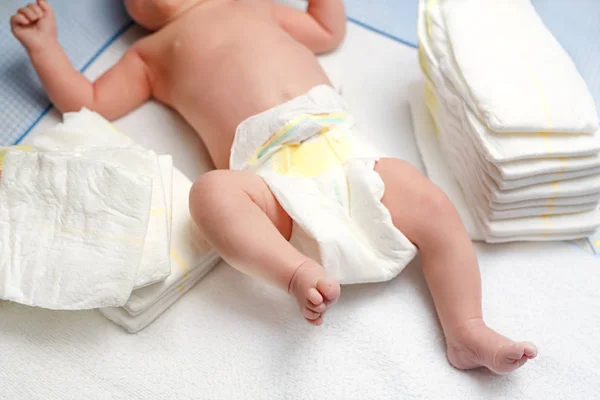 Fötter av nyfödda barn på skötbord med blöjor. Söt liten flicka eller pojke två veckor gammal. Torr och frisk kropp och hud koncept. Barndaghem. — Stockfoto