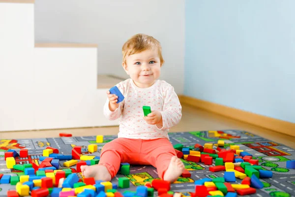 Schattig meisje dat met educatief speelgoed speelt. Gelukkig gezond kind hebben plezier met kleurrijke verschillende houten blokken thuis in de huiselijke kamer. Baby leren kleuren en vormen — Stockfoto