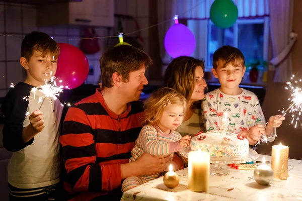 En förtjusande liten flicka som firar sin andra födelsedag. Baby barn, två barn pojkar bröder, mor och far tillsammans med tårta och ljus. Glad frisk familj porträtt med tre barn — Stockfoto