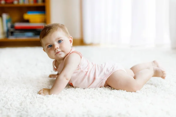 Pouco engraçado bebê menina levantando corpo e aprender a rastejar. — Fotografia de Stock