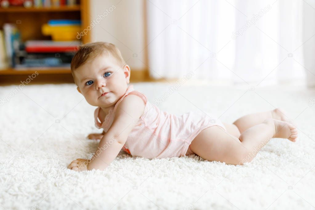 Little funny baby girl lifting body and learning to crawl.