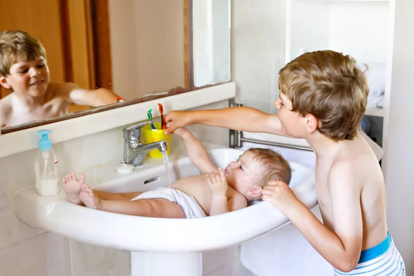 Cute adorable baby taking bath in washing sink and grab water tap. — Stock Photo, Image