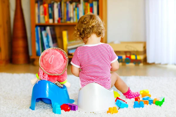 Primer plano de un niño pequeño y lindo de 12 meses sentado en el orinal. Niño jugando con muñeco de juguete. Concepto de entrenamiento de baño. Aprendizaje del bebé, pasos de desarrollo — Foto de Stock