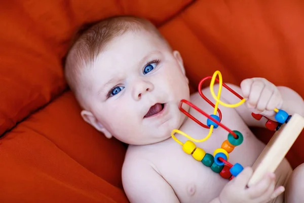 Adorabile neonato che gioca con il giocattolo di sonaglio educativo in legno colorato — Foto Stock