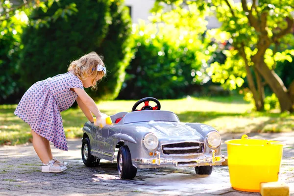Ładny wspaniały maluch Dziewczyna mycie duży stary zabawka samochód w lato Gar — Zdjęcie stockowe