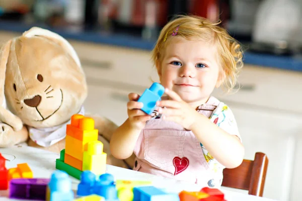 Adorabile bambina con il coniglietto peluche preferito che gioca con i giocattoli educativi nella scuola materna. Buon bambino sano divertirsi con blocchi di plastica colorati diversi a casa. Carino imparare bambino creare. — Foto Stock