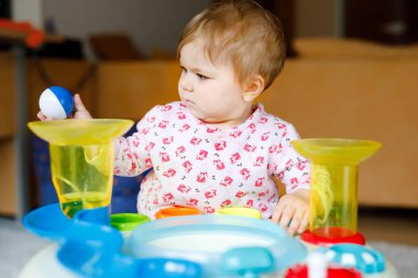Evde ya da çocuk odasında eğitici oyuncaklarla oynayan sevimli, güzel bir kız bebek. Mutlu sağlıklı çocuk eğleniyor ve farklı renkli plastik topları ayırıyor. Çocuk farklı yetenekler öğreniyor