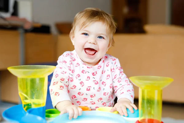 Adorable linda y hermosa niña jugando con juguetes educativos en casa o en la guardería. Feliz niño sano divirtiéndose y clasificando coloridas bolas de plástico diferentes. Niño aprendiendo diferentes habilidades — Foto de Stock