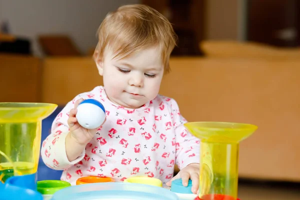 Adorable linda y hermosa niña jugando con juguetes educativos en casa o en la guardería. Feliz niño sano divirtiéndose y clasificando coloridas bolas de plástico diferentes. Niño aprendiendo diferentes habilidades — Foto de Stock