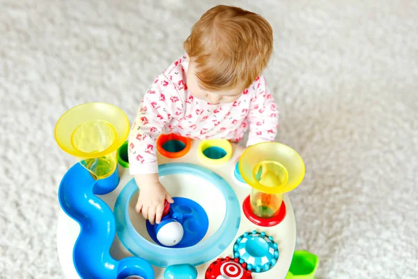 Adorable linda y hermosa niña jugando con juguetes educativos en casa o en la guardería. Feliz niño sano divirtiéndose y clasificando coloridas bolas de plástico diferentes. Niño aprendiendo diferentes habilidades —  Fotos de Stock