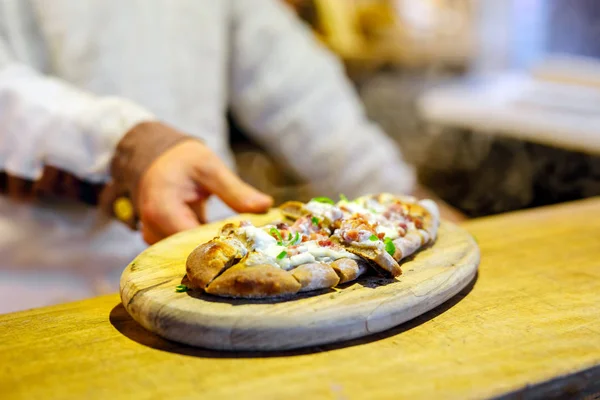 Tradiční chléb s kyselým krémem a šunkou na německém vánočním trhu. Na veletrhu Xmas v Německu se ztěsní čerstvě upečený preclík a ruce člověka — Stock fotografie