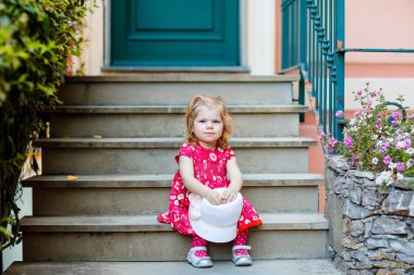 Pembe elbiseli, moda elbiseli, diz altı çoraplı ve şapkalı güzel küçük bir kız çocuğunun portresi. Renkli evin önünde poz veren mutlu sağlıklı bebek..