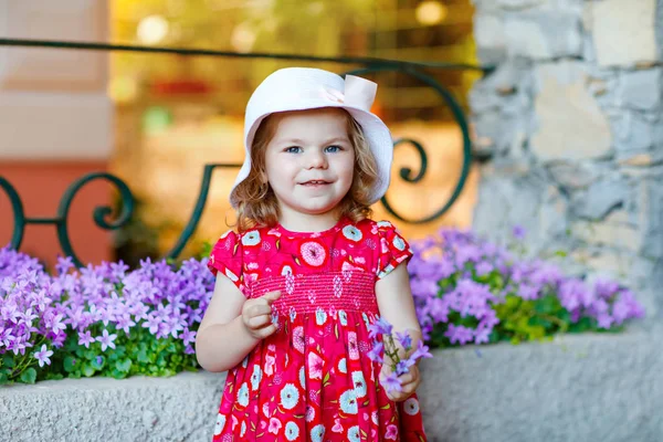 Pembe elbiseli, moda elbiseli, diz altı çoraplı ve şapkalı güzel küçük bir kız çocuğunun portresi. Renkli evin önünde poz veren mutlu sağlıklı bebek..