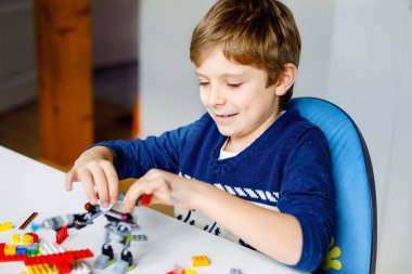 Renkli plastik bloklar çok oynayan küçük sarışın çocuk. Sevimli okul çocuk çocuk bina ve robot oluşturma ile eğlenmek. Yaratıcı eğlence modern teknik ve robotik.
