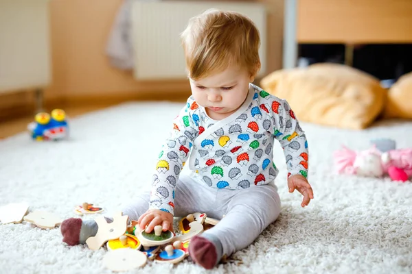 家庭や保育園で木製のパズルのような教育用のおもちゃで遊んで豪華なかわいい美しい小さな赤ちゃんの女の子。カラフルなさまざまなおもちゃで楽しんでいる幸せな健康的な子供。子供は異なるスキルを学ぶ — ストック写真