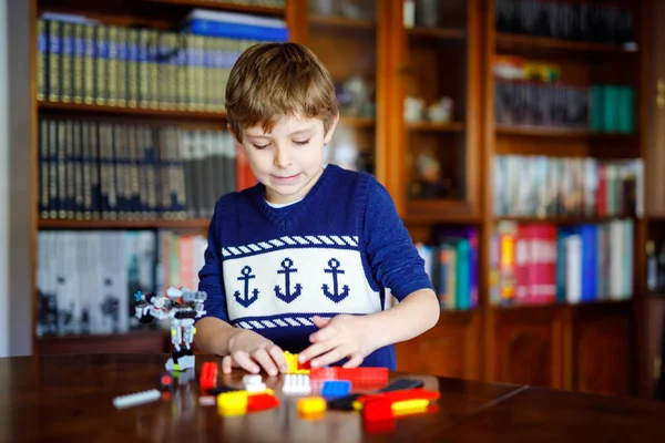 Lilla blonda barn leker med massor av färgglada plast block. Söt skol unge pojke ha kul med att bygga och skapa robot. Kreativ fritid modern Technic och Robotic. — Stockfoto
