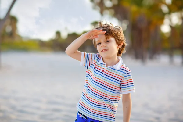 Adorable active little kid boy having fun on Miami beach, Key Biscayne. Happy cute child relaxing, playing with sand and enjoying sunny warm day near palms and ocean — Stock Photo, Image