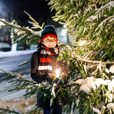 Renkli giysiler içinde kar yağarken dışarıda oynayan komik küçük çocuk. Soğuk karlı günlerde, kışın çocuklarla aktif eğlence. Mutlu çocuk Almanya 'da Noel pazarında