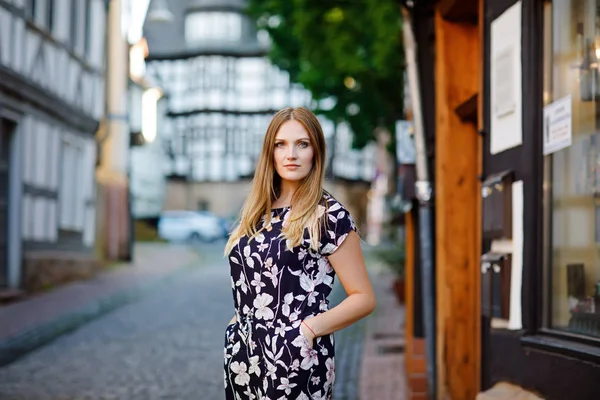 Belle jeune femme aux cheveux longs en robe d'été se promenant dans la ville allemande. Fille heureuse profitant de la marche dans une jolie petite ville fachwerk avec de vieilles maisons en Allemagne. — Photo