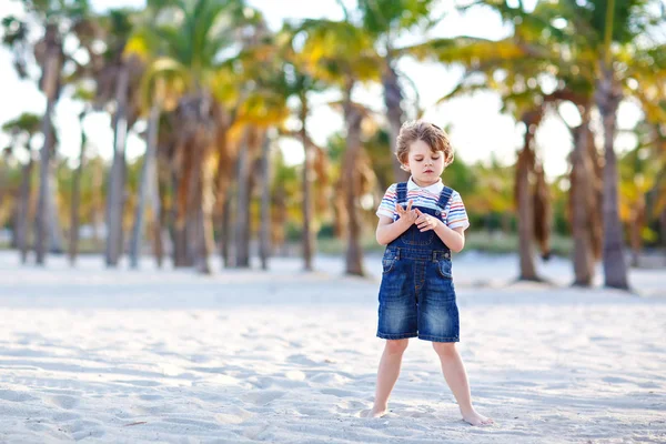 Adorable active little kid boy having fun on Miami beach, Key Biscayne. Happy cute child relaxing, playing with sand and enjoying sunny warm day near palms and ocean — Stock Photo, Image