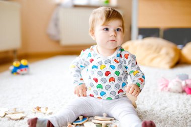 Evde ya da çocuk odasında ahşap yapboz gibi eğitici oyuncaklarla oynayan güzel bir kız bebek. Mutlu sağlıklı çocuk renkli oyuncaklarla eğleniyor. Çocuk farklı yetenekler öğreniyor