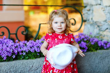 Pembe elbiseli, moda elbiseli, diz altı çoraplı ve şapkalı güzel küçük bir kız çocuğunun portresi. Renkli evin önünde poz veren mutlu sağlıklı bebek..