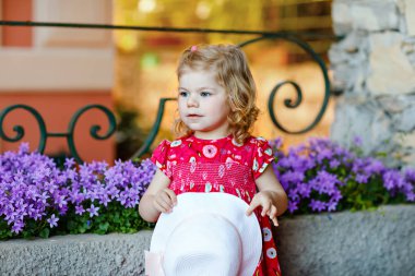 Pembe elbiseli, moda elbiseli, diz altı çoraplı ve şapkalı güzel küçük bir kız çocuğunun portresi. Renkli evin önünde poz veren mutlu sağlıklı bebek..