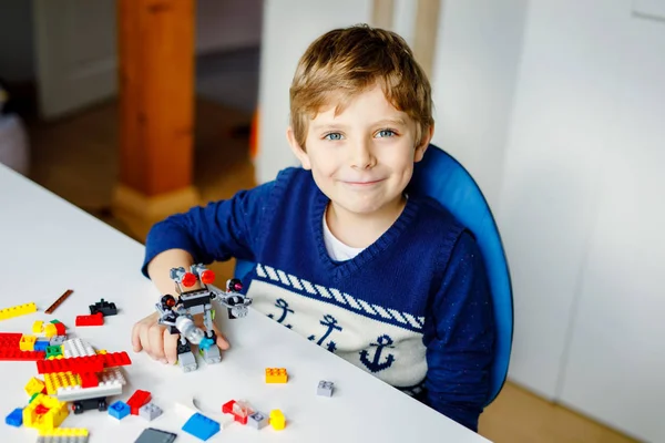 Lilla blonda barn leker med massor av färgglada plast block. Söt skol unge pojke ha kul med att bygga och skapa robot. Kreativ fritid modern Technic och Robotic. — Stockfoto