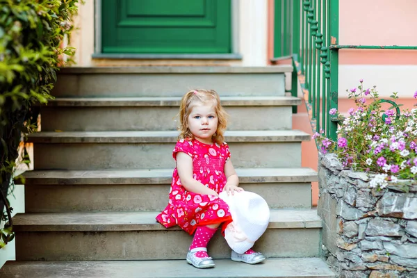 Portrait of beautiful little gorgeus lovely toddler girl in pink summer look clothes, fashion dress, knee socks and hat. Happy healthy baby child posing infront of colorful house. — Stock Photo, Image