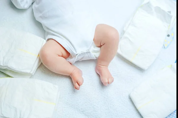 Fötter av nyfödda barn på skötbord med blöjor. Söt liten flicka eller pojke två veckor gammal. Torr och frisk kropp och hud koncept. Barndaghem. — Stockfoto