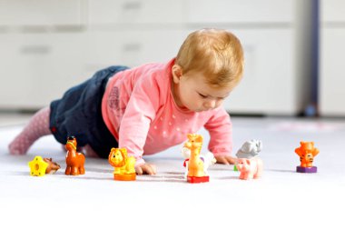 Sevimli bir bebek inek, at, koyun, köpek ve zürafa, fil ve maymun gibi vahşi hayvanlarla oynuyor. Mutlu sağlıklı çocuk evde renkli oyuncaklarla eğleniyor.