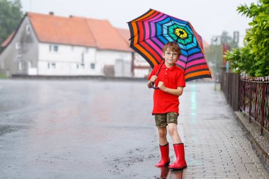 Kızıl yağmur botları ve şemsiye ile yürüyüş çocuk çocuk