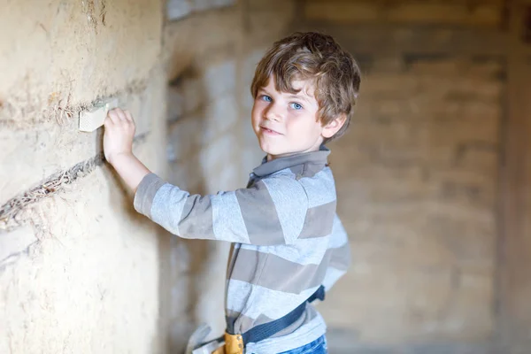 Liten unge pojke hjälper med leksak verktyg på byggarbeten webbplats. — Stockfoto