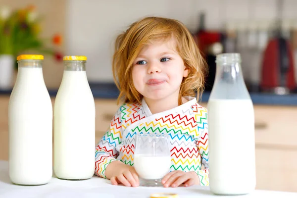 Schattig peutermeisje dat koemelk drinkt als ontbijt. Schattige kleine dochter met veel flessen. Gezond kind dat melk als gezondheidscalciumbron heeft. Kind thuis of in de kinderkamer in de ochtend. — Stockfoto