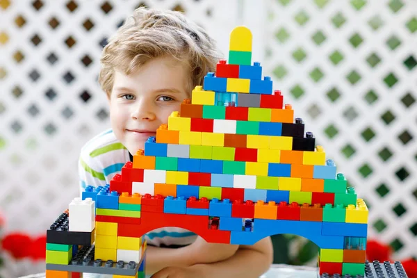 Маленький блондин ребенок и мальчик играет с большим количеством красочных пластиковых блоков. — стоковое фото