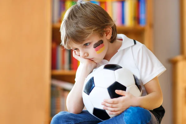 Triest en niet gelukkig klein kind met voetbal over verloren voetbal of voetbalwedstrijd. kind na het kijken van wedstrijd op tv — Stockfoto