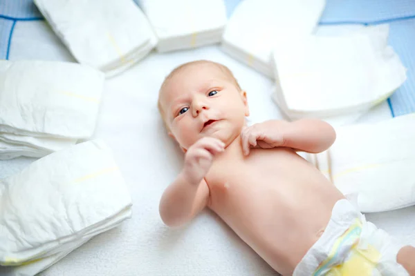 Милый очаровательный новорожденный ребенок на столе для переодевания с подгузниками. Симпатичная девочка или мальчик смотрит в камеру. Сухая и здоровая концепция тела и кожи. Детский сад. — стоковое фото
