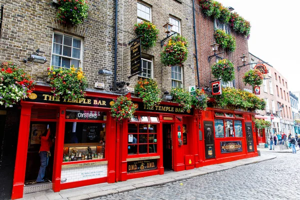 DUBLIN, IRELAND - JULY 1, 2019: Temple Bar is a famous landmark in Dublins cultural quarter visited by thousands of tourists every year. The Temple Bar in the center of the Irish capital - men women — Stock Photo, Image