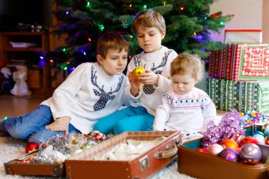İki küçük çocuk çocuklar ve bebek kız eski vintage oyuncak ve topları ile Noel ağacı süsleme.