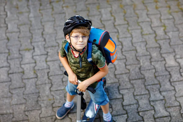Twee school jongen jongens in veiligheidshelm rijden met scooter in de stad met rugzak op zonnige dag. Gelukkige kinderen in kleurrijke kleren fietsen op weg naar school. Onherkenbaar gezichten van boven naar achteren — Stockfoto