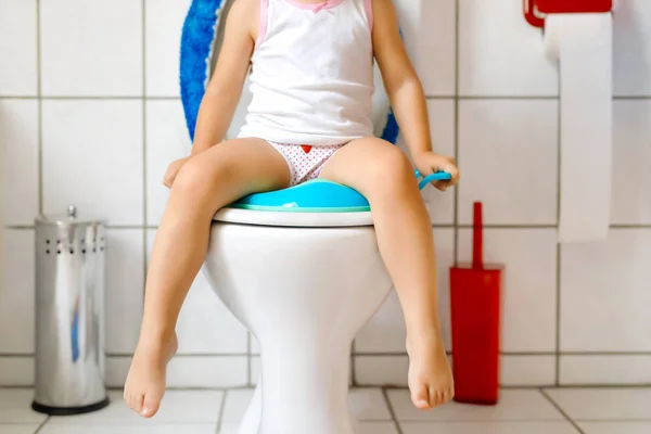 Primer plano del niño pequeño y lindo bebé niña sentada en el asiento del inodoro wc. Entrenamiento en orinal para niños pequeños. El rostro irreconocible del niño — Foto de Stock