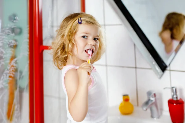 Schattig schattig peuter meisje met tandenborstel en poetsen eerste tanden in de badkamer na het slapen. Prachtige baby kind leren om melktand schoon te maken. Ochtend gezonde hygiëne routine voor kinderen — Stockfoto