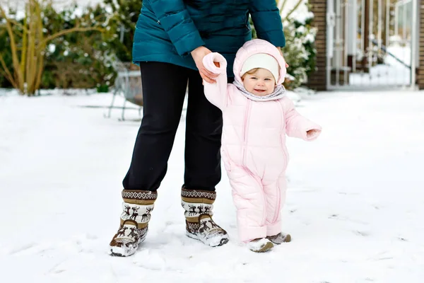 Schattig klein meisje dat 's winters de eerste stappen zet met moeder. Leuke peuter leren lopen. — Stockfoto