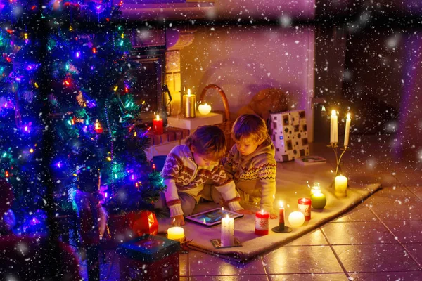 Dua anak kecil duduk di dekat perapian di rumah pada hari Natal — Stok Foto