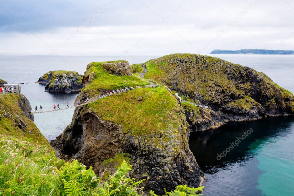 Carrick-a-Rede Rope Bridge, famous rope bridge near Ballintoy in County Antrim, Northern Ireland. Tourist attraction, bridge to small island on cloudy day.