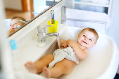 Alarak şirin bebek yıkama lavabo banyo ve musluk suyu yakala.