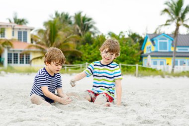 İki küçük çocuk tropik sahilde eğleniyor.